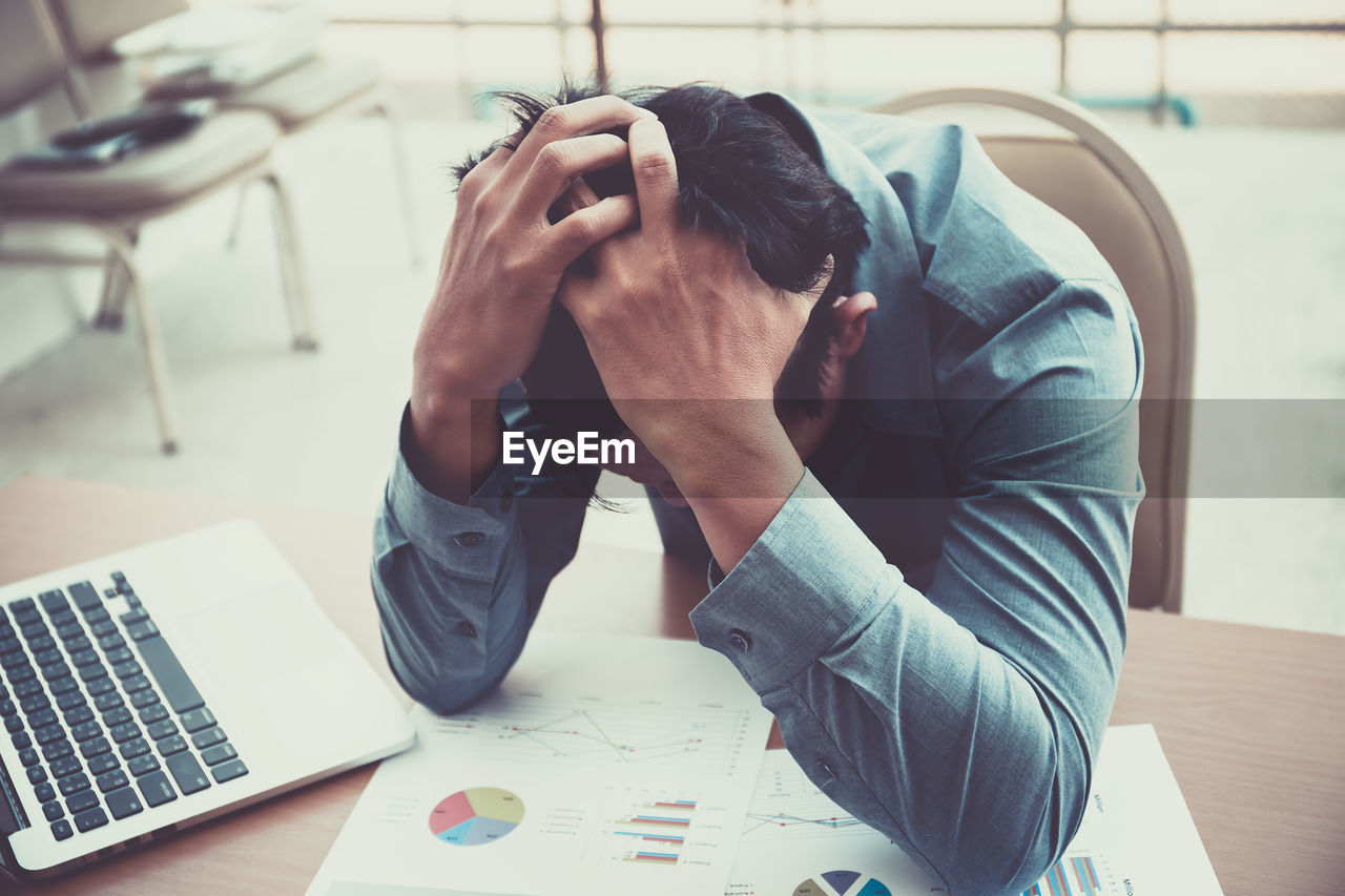 High angle view of frustrated businessman with head in hands