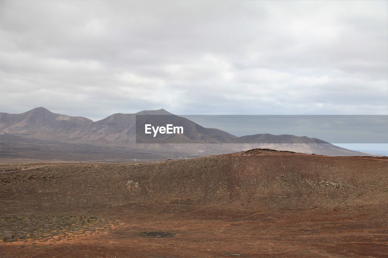 Scenic view of arid landscape mountains against sky