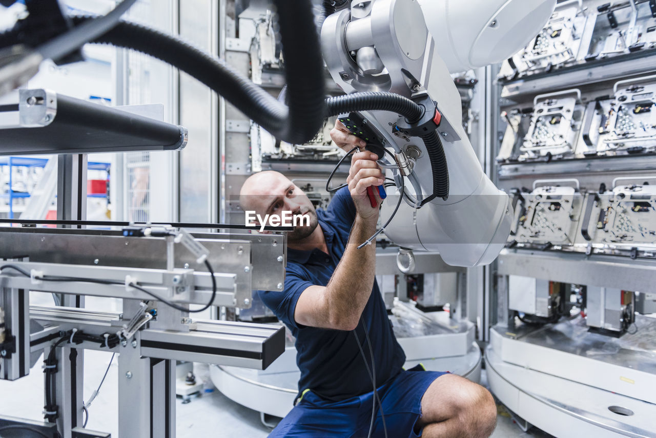 Man working at industrial robot in modern factory