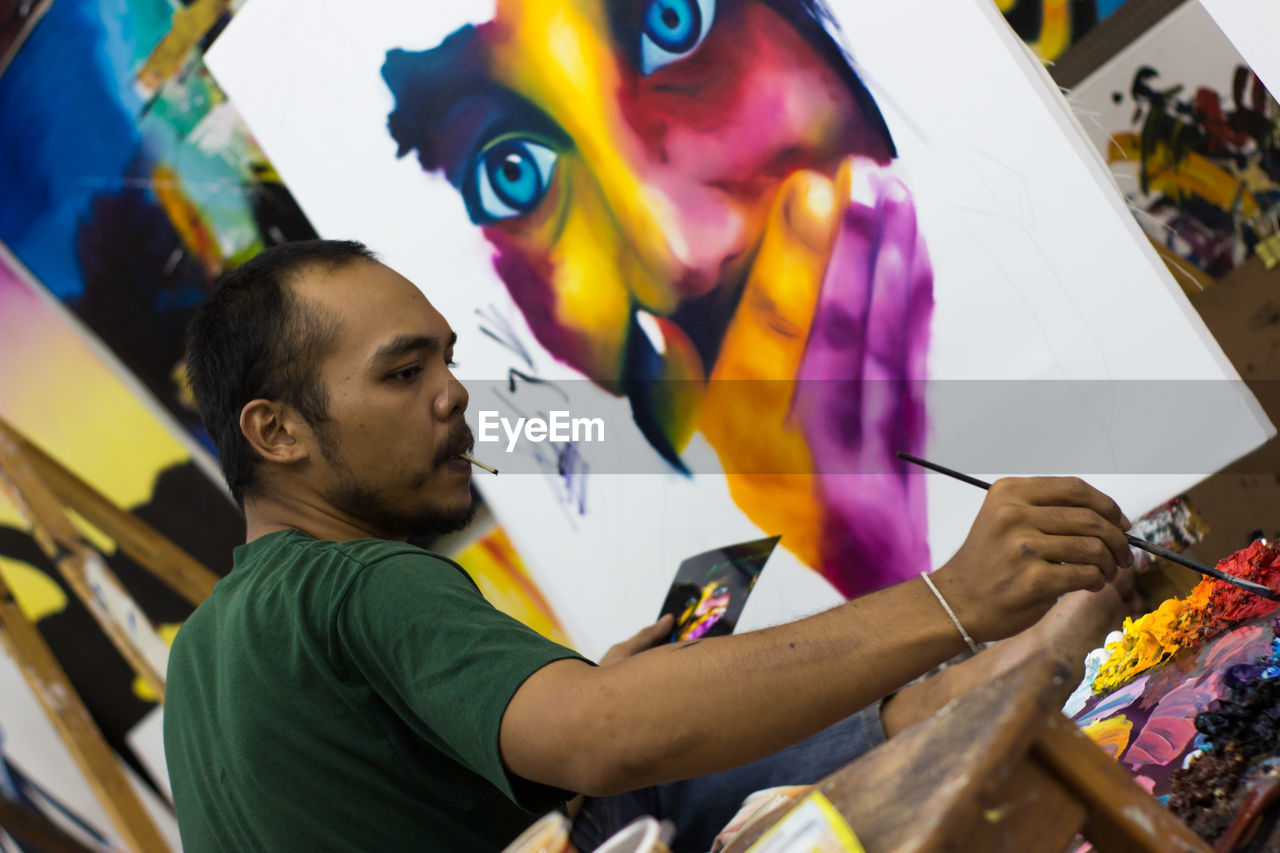 HIGH ANGLE VIEW OF WOMAN HOLDING MULTI COLORED UMBRELLAS