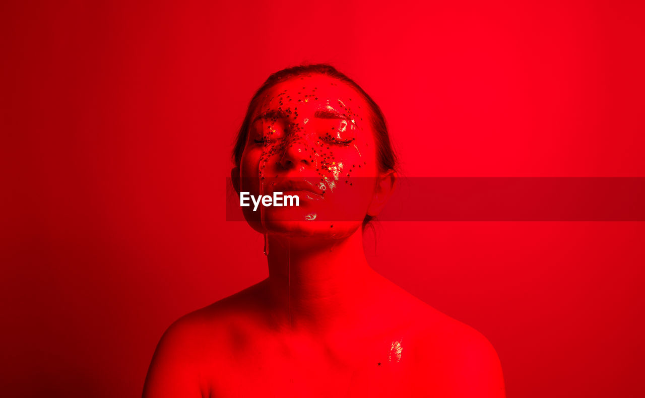 Close-up of woman with water and star shape decoration against red background