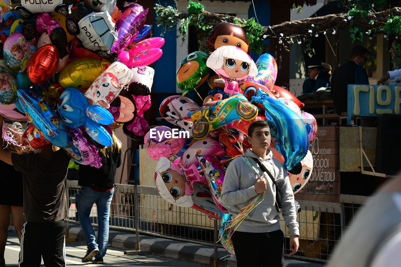 PEOPLE STANDING IN MULTI COLORED UMBRELLAS