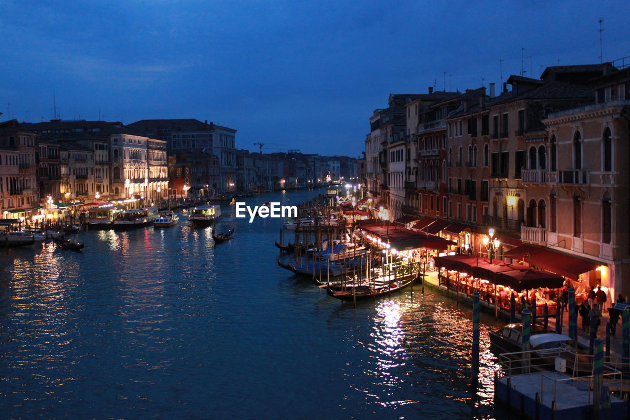 Gondolas in grand canal amidst buildings against sky at dusk