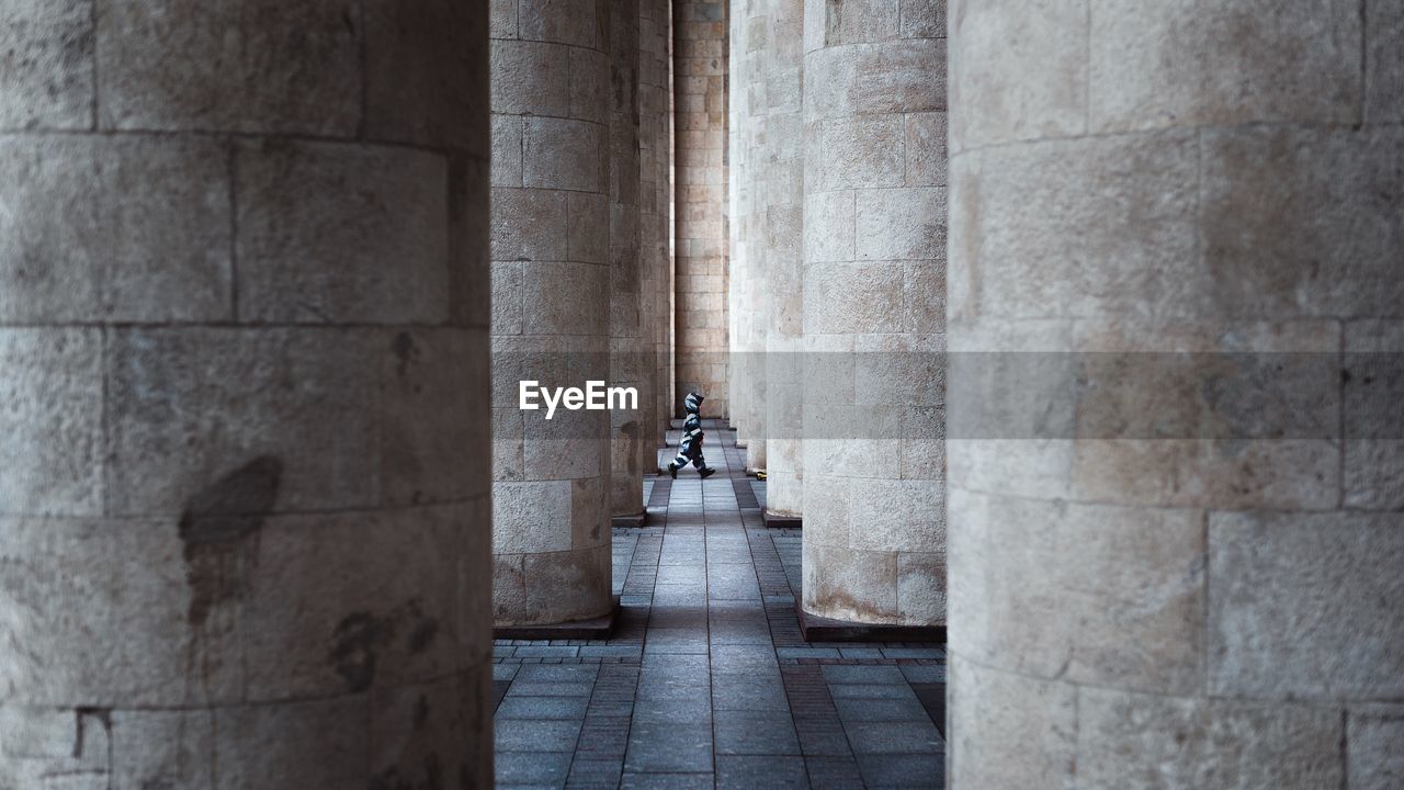 Side view of child walking amidst columns