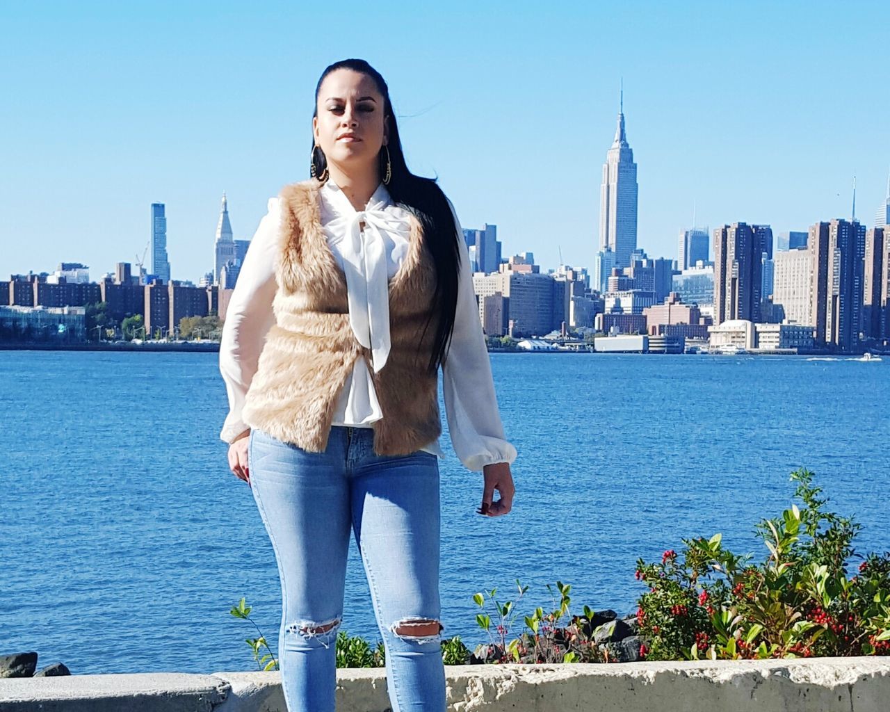 Young woman standing by east river against cityscape