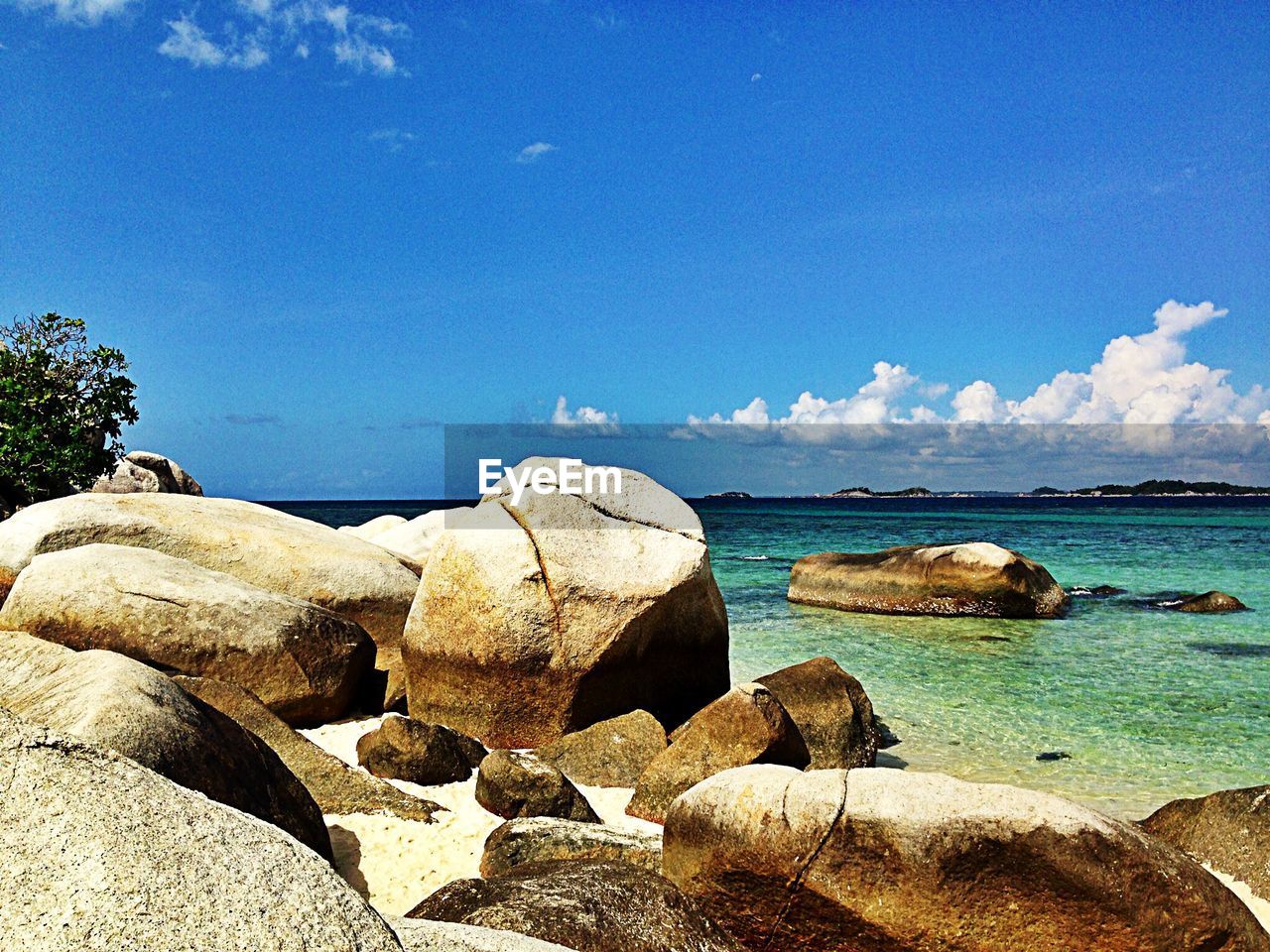 Scenic view of rocks on beach against blue sky