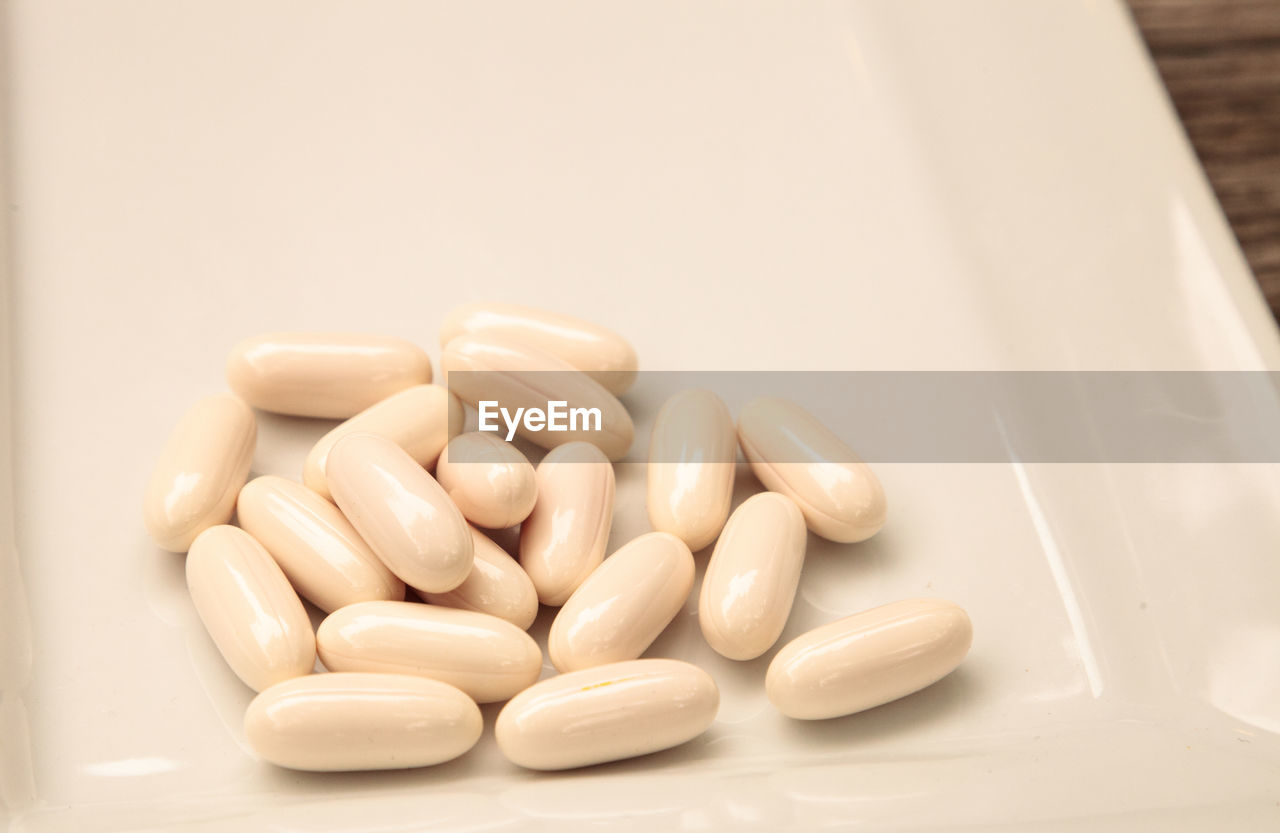 White gel capsules of vitamin co q-10 also called coenzyme q10 displayed on a white surface.