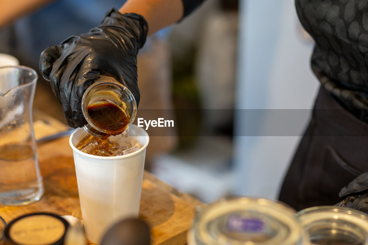 Close-up of hand pouring coffee in glass on table