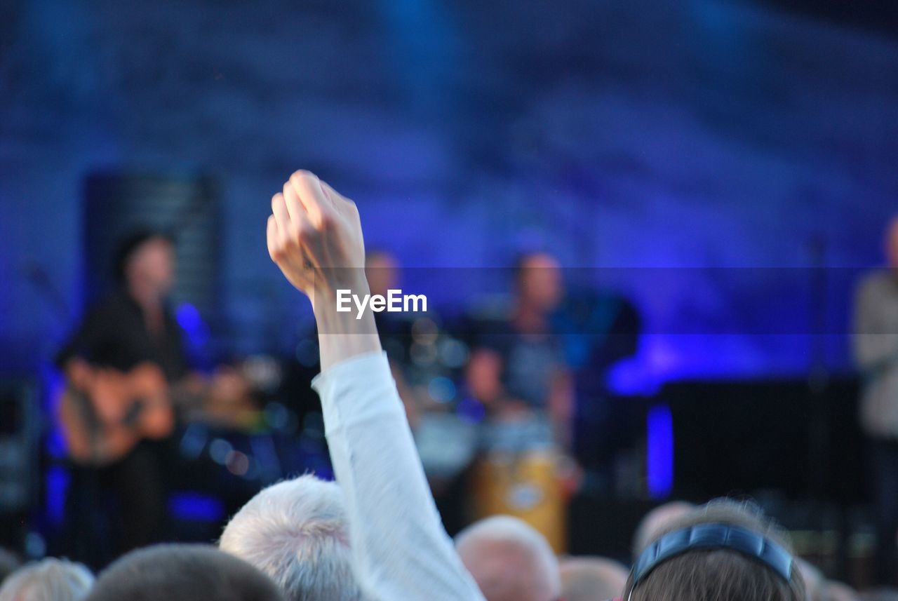 Man with hand raised in crowd during concert