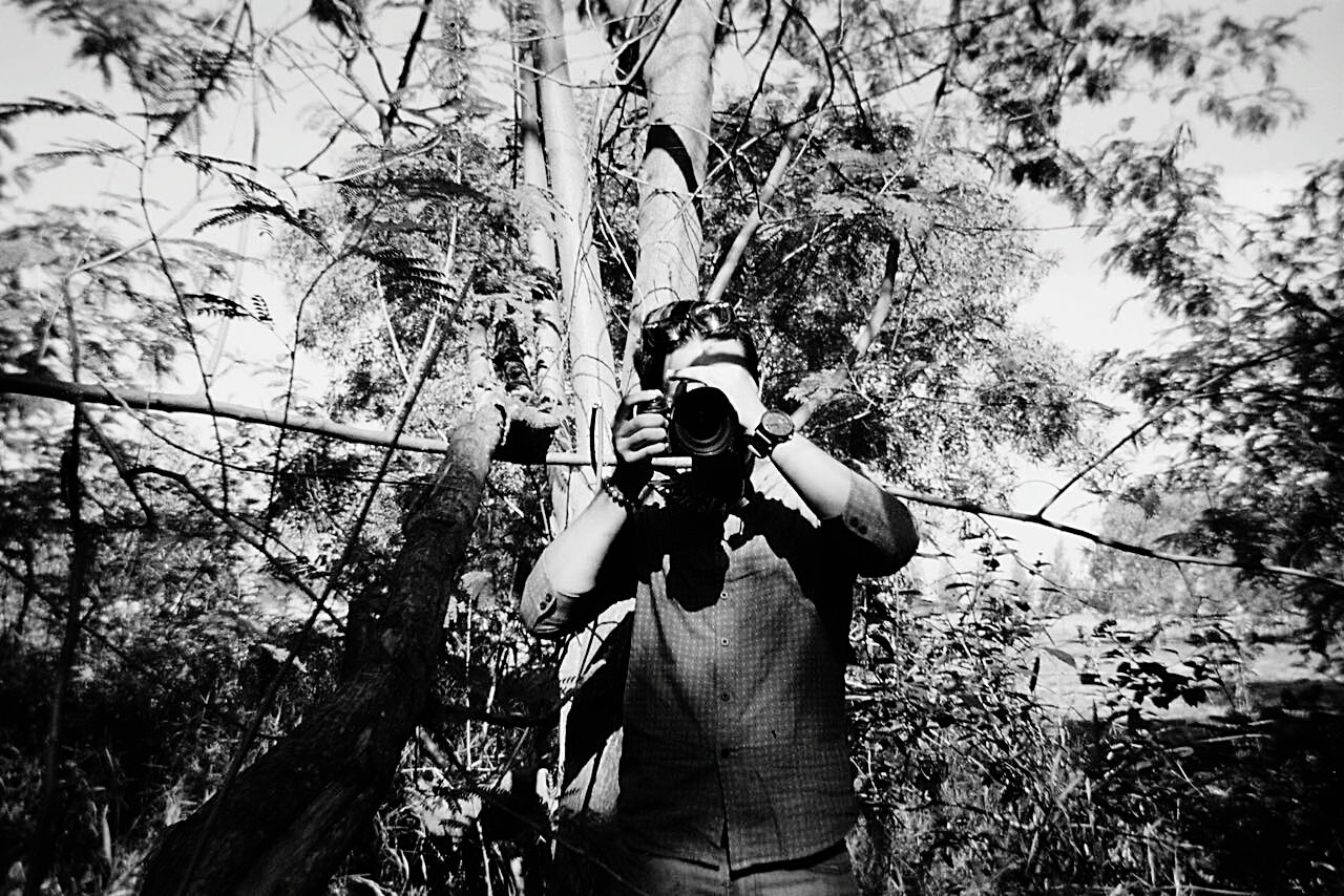 MAN PHOTOGRAPHING WITH CAMERA AGAINST SKY