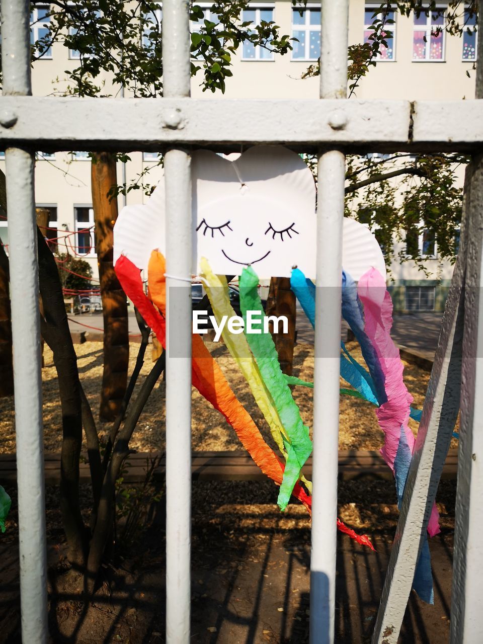 MULTI COLORED FLAGS HANGING ON RAILING AGAINST TREES