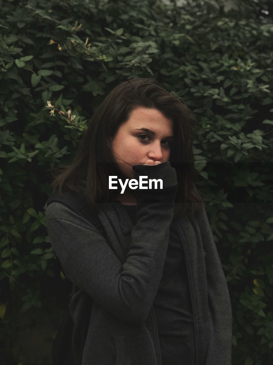 Portrait of young woman standing against plants