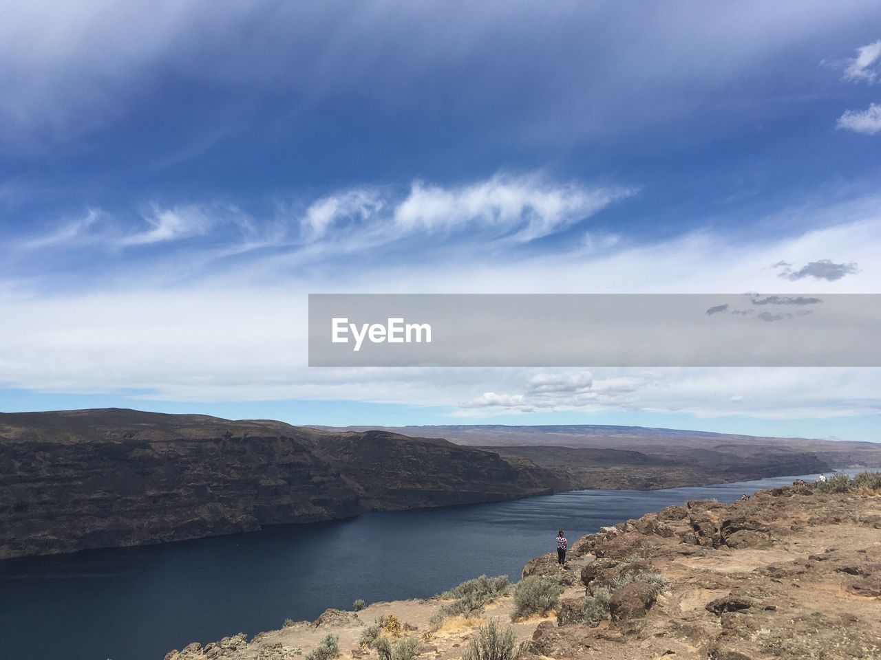 Rear view of woman standing on cliff by columbia river against sky