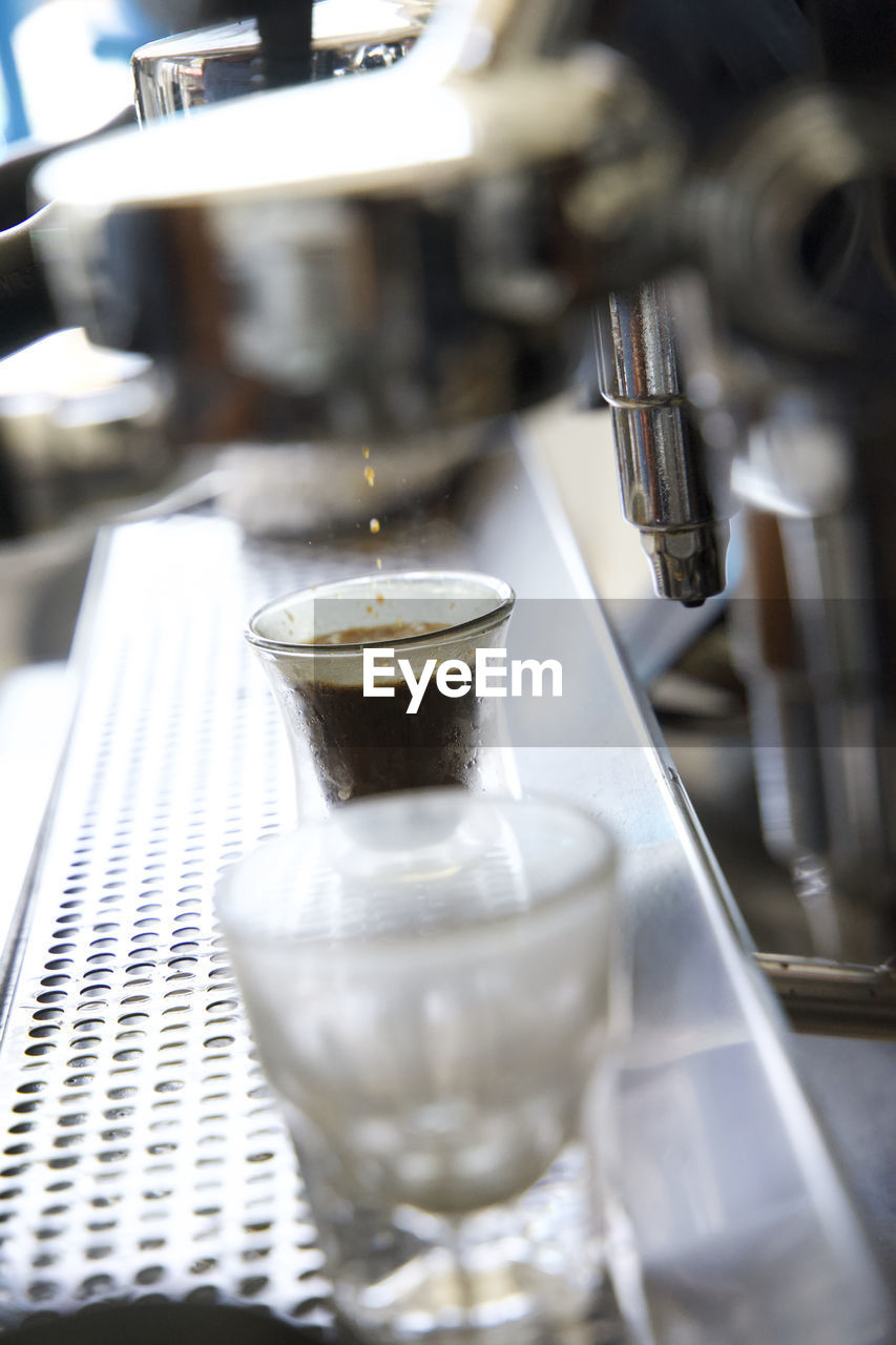 Close up of espresso maker pouring espresso into a small glass in a coffee shop