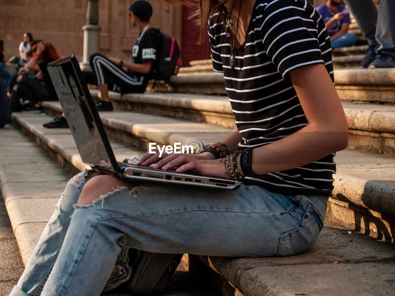 Midsection of woman using laptop while sitting on staircase