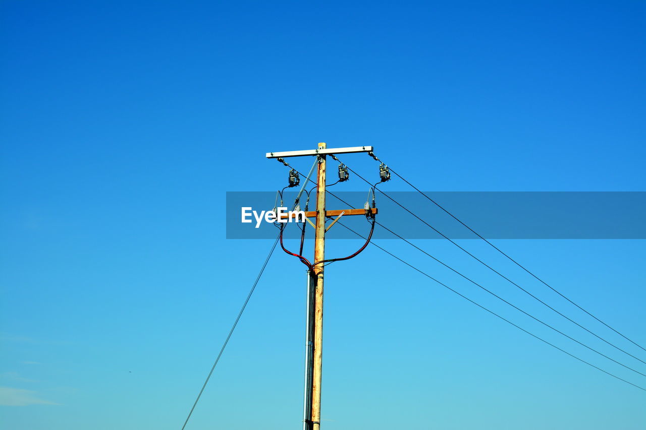 High section of electric pylon against blue sky