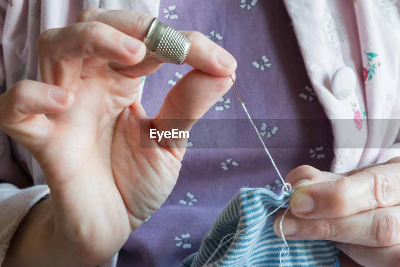 Midsection of woman stitching textile 