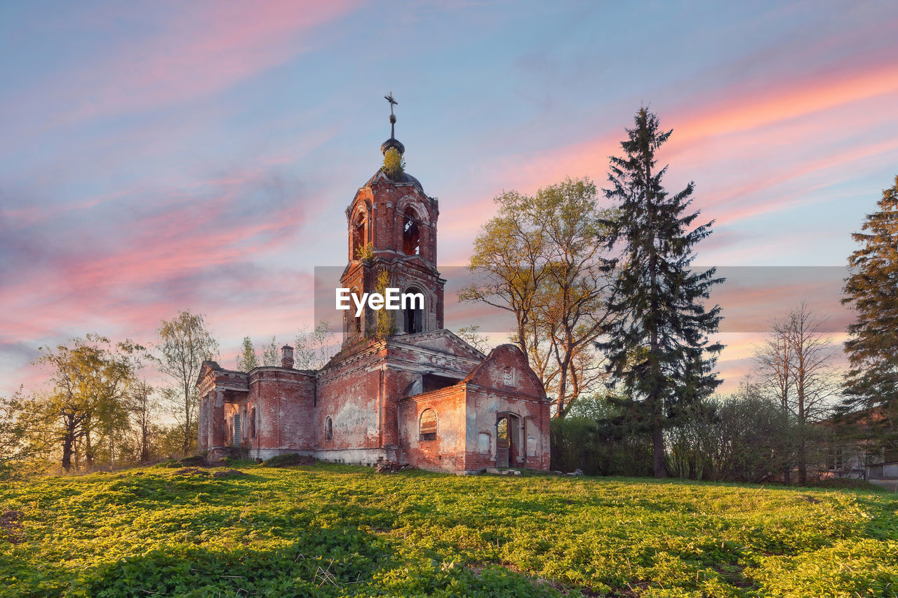 Abandoned brick orthodox church with a portico and columns at sunset