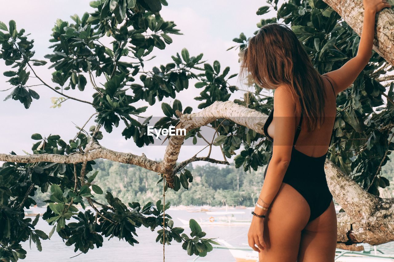 full length of young woman in bikini while standing against plants