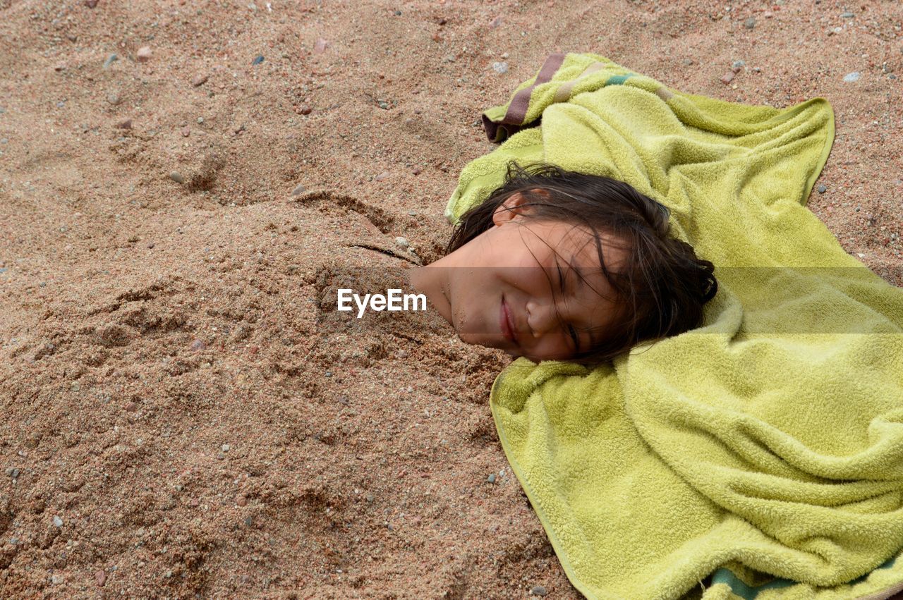 Close-up of girl buried in sand