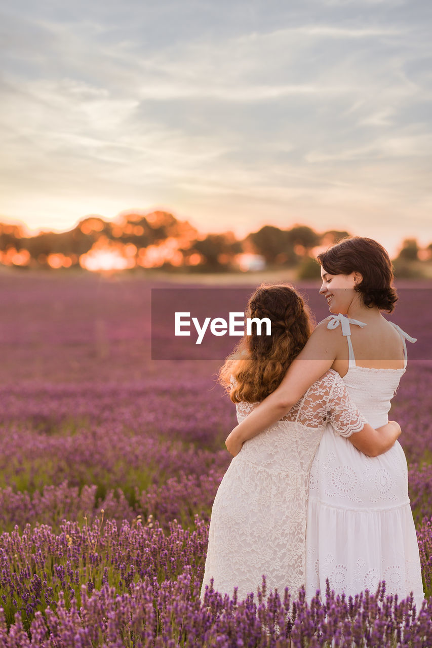 Rear view of lesbian couple standing on flower field