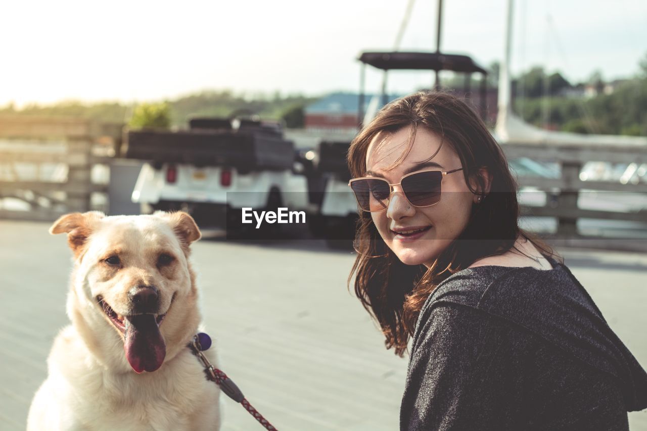 Portrait of smiling young woman holding dog at beach