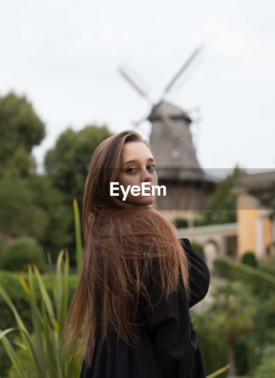 Portrait of smiling young woman standing against sky