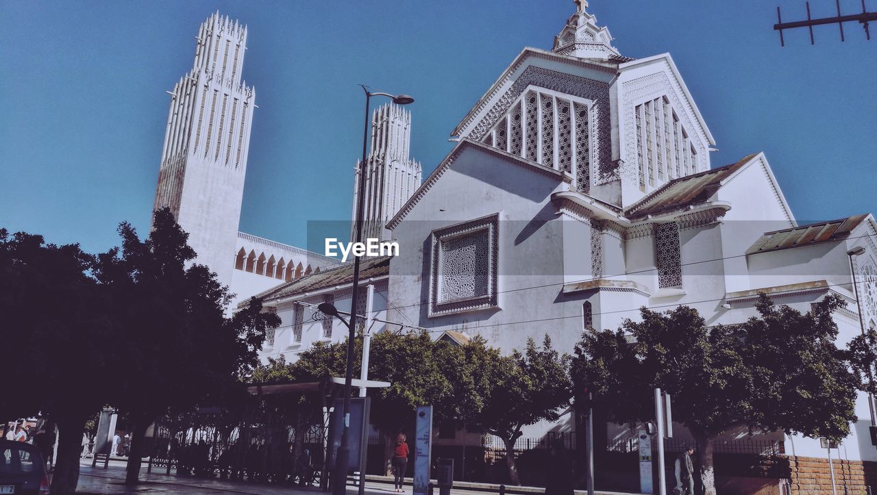 Low angle view of trees and buildings against clear sky