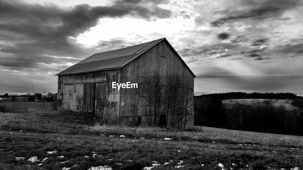 Abandoned barn on field against sky during winter