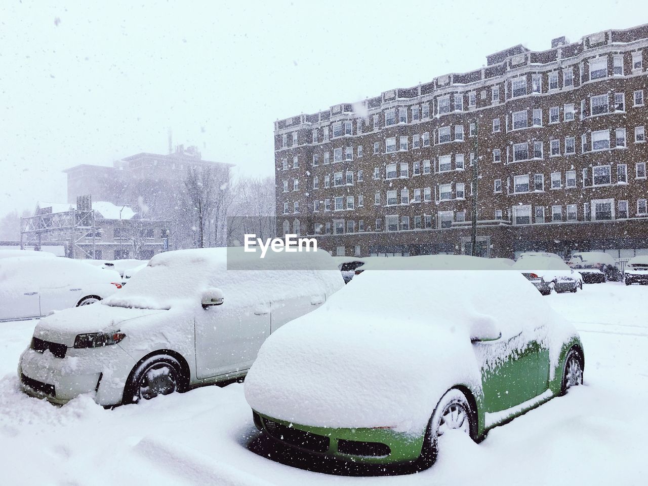 Snow covered cars against buildings in city during winter