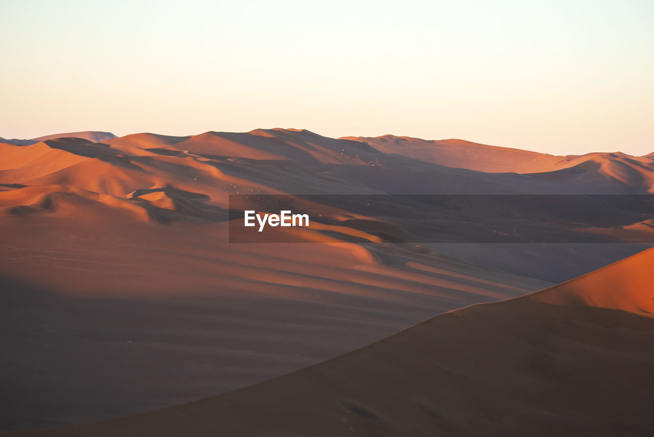 SCENIC VIEW OF DESERT AGAINST CLEAR SKY AT SUNSET