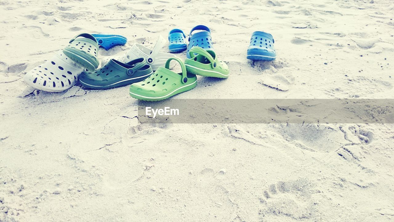 HIGH ANGLE VIEW OF SHOES ON SANDY BEACH