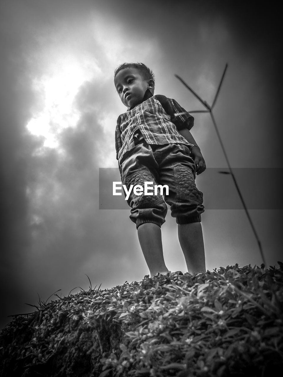 LOW ANGLE VIEW OF BOY AGAINST CLOUDY SKY