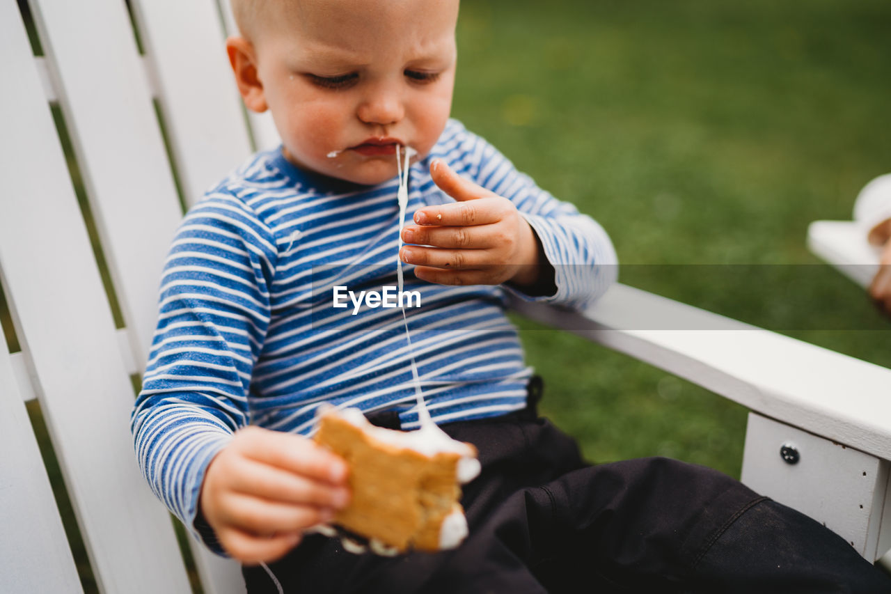 Male toddler eating smores with melted marshmallows