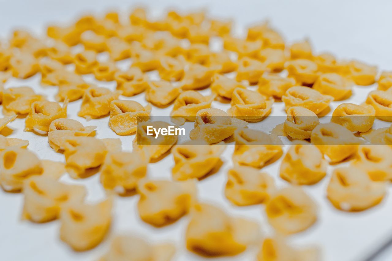Rows of raw traditional italian tortellini placed on baking pan in bright kitchen