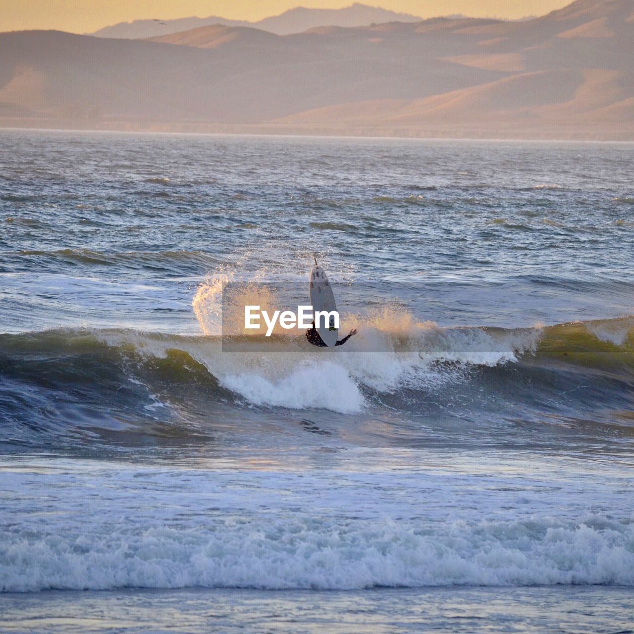 Man surfing in sea against mountains