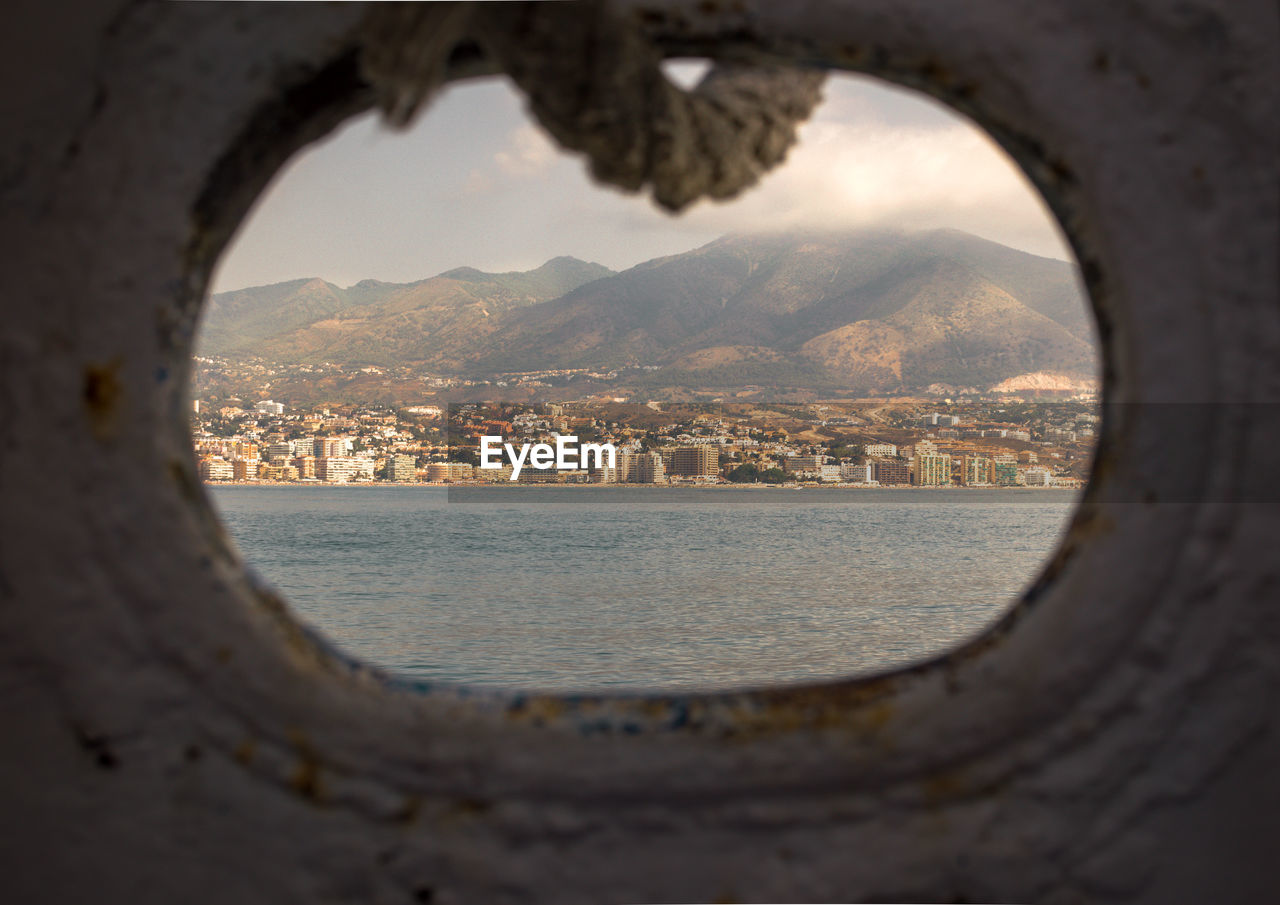 CITYSCAPE BY SEA SEEN THROUGH WINDOW