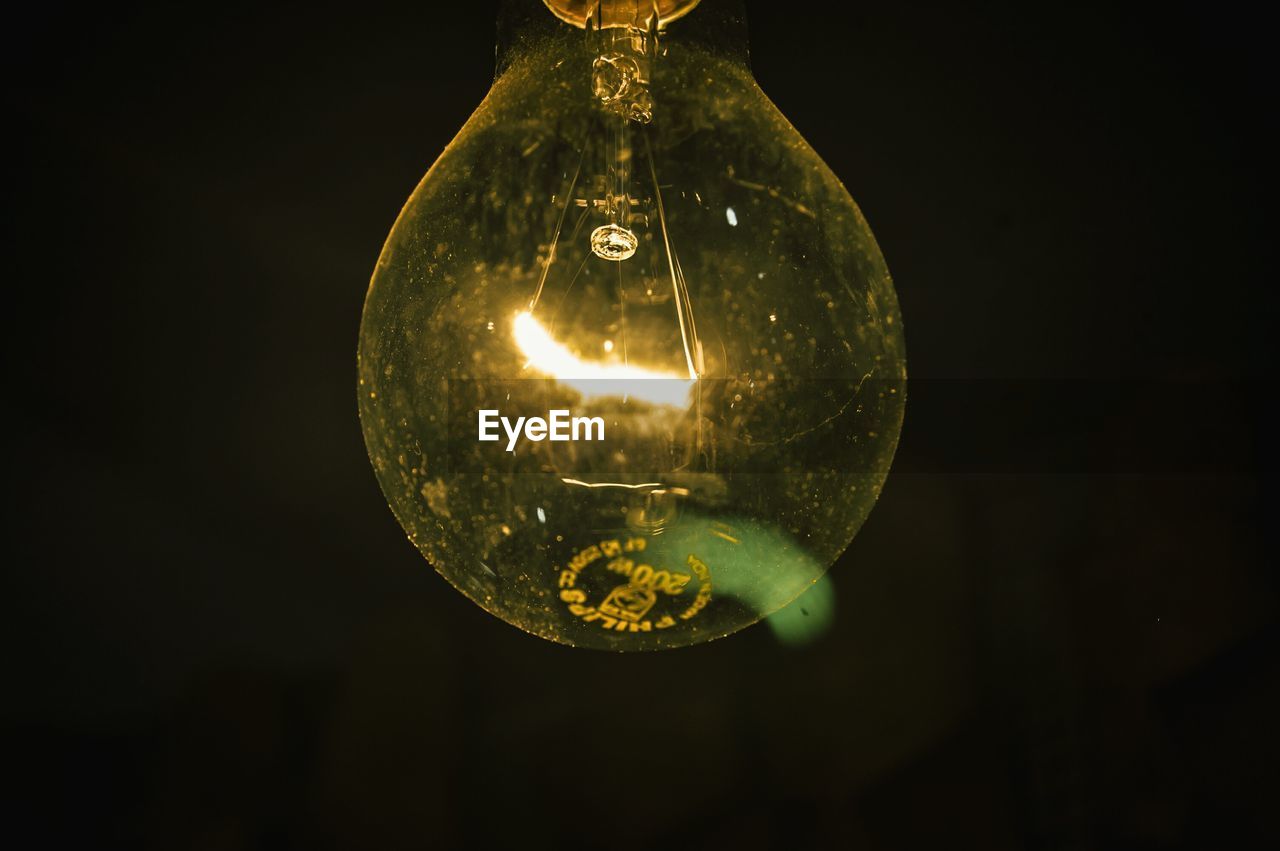 LOW ANGLE VIEW OF ILLUMINATED LIGHT BULB HANGING ON BACKGROUND