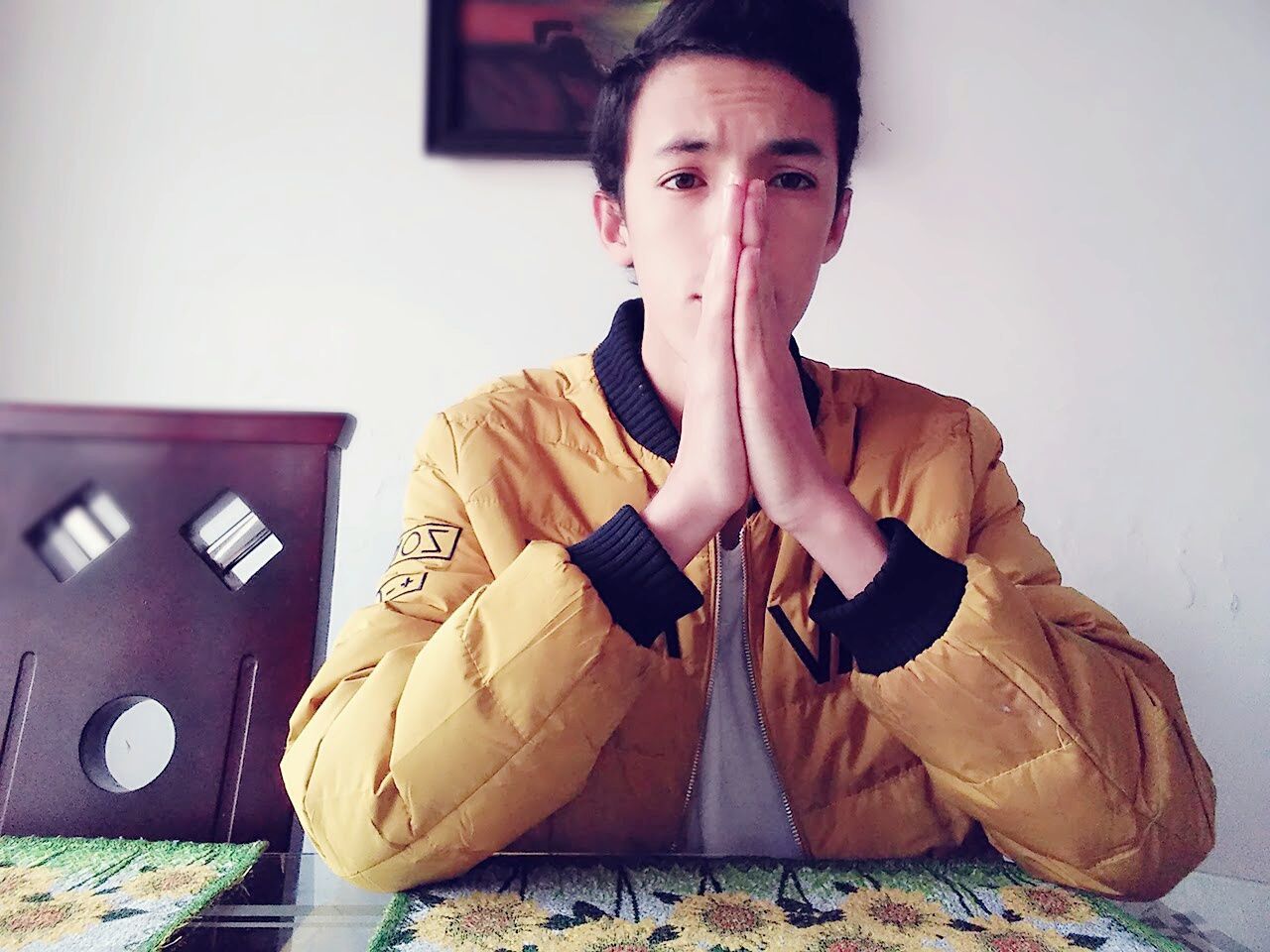 Young man with hands clasped sitting at dining table