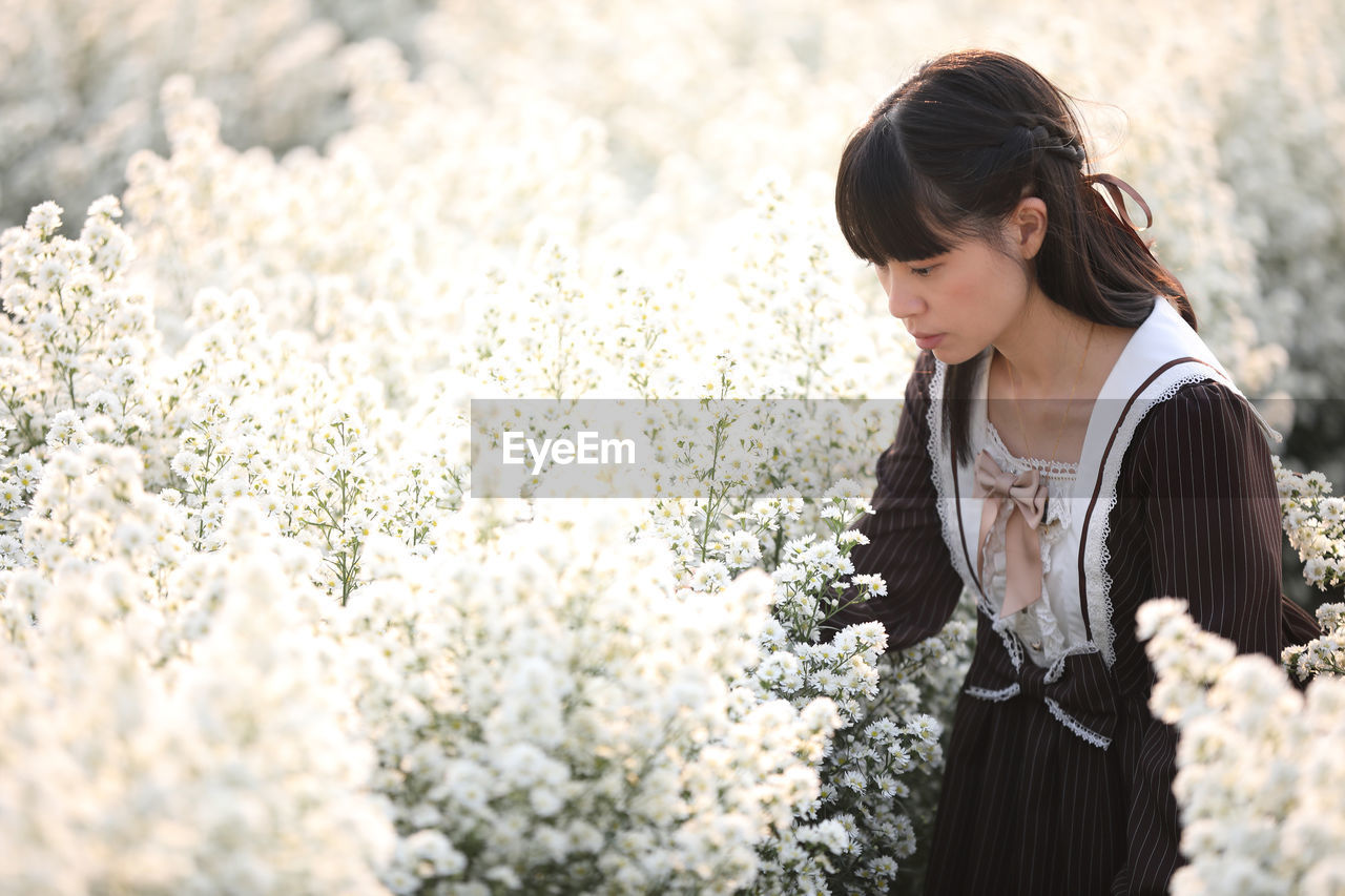 Young woman standing amidst flowering plants