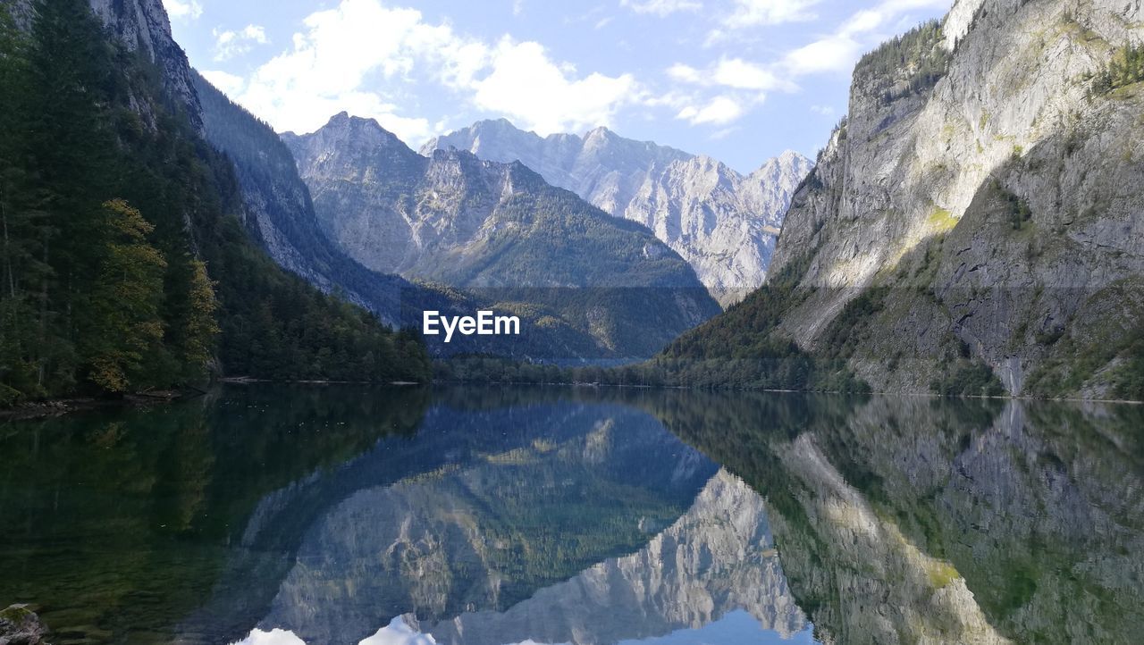 Wide scenic view of lake surrounded by mountain reflected in water