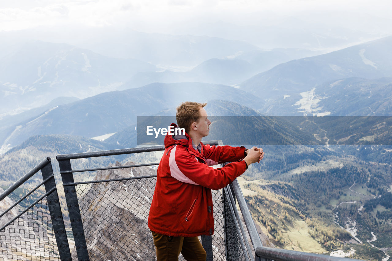 Millennial guy enjoys mountain views of alps from observation deck