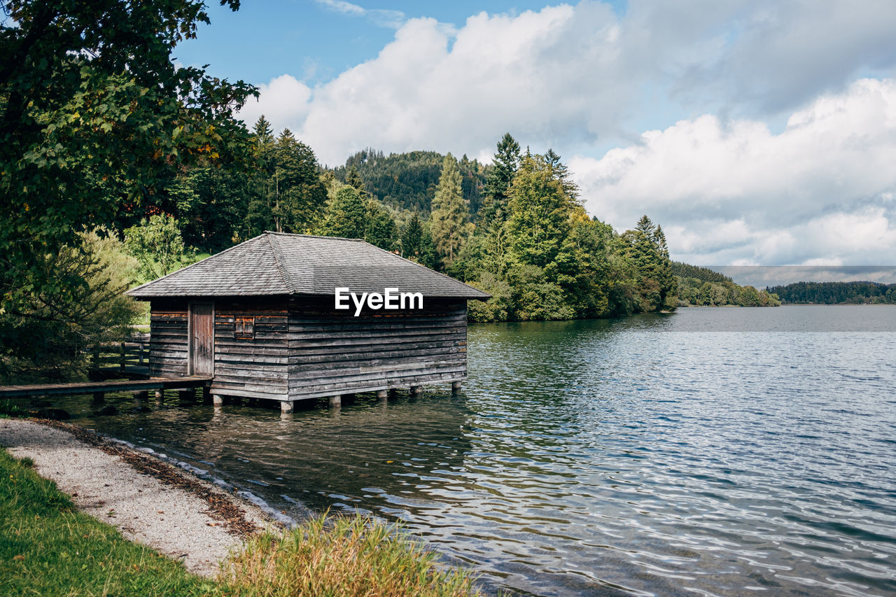 Wooden boat house in lake in front of forest trees