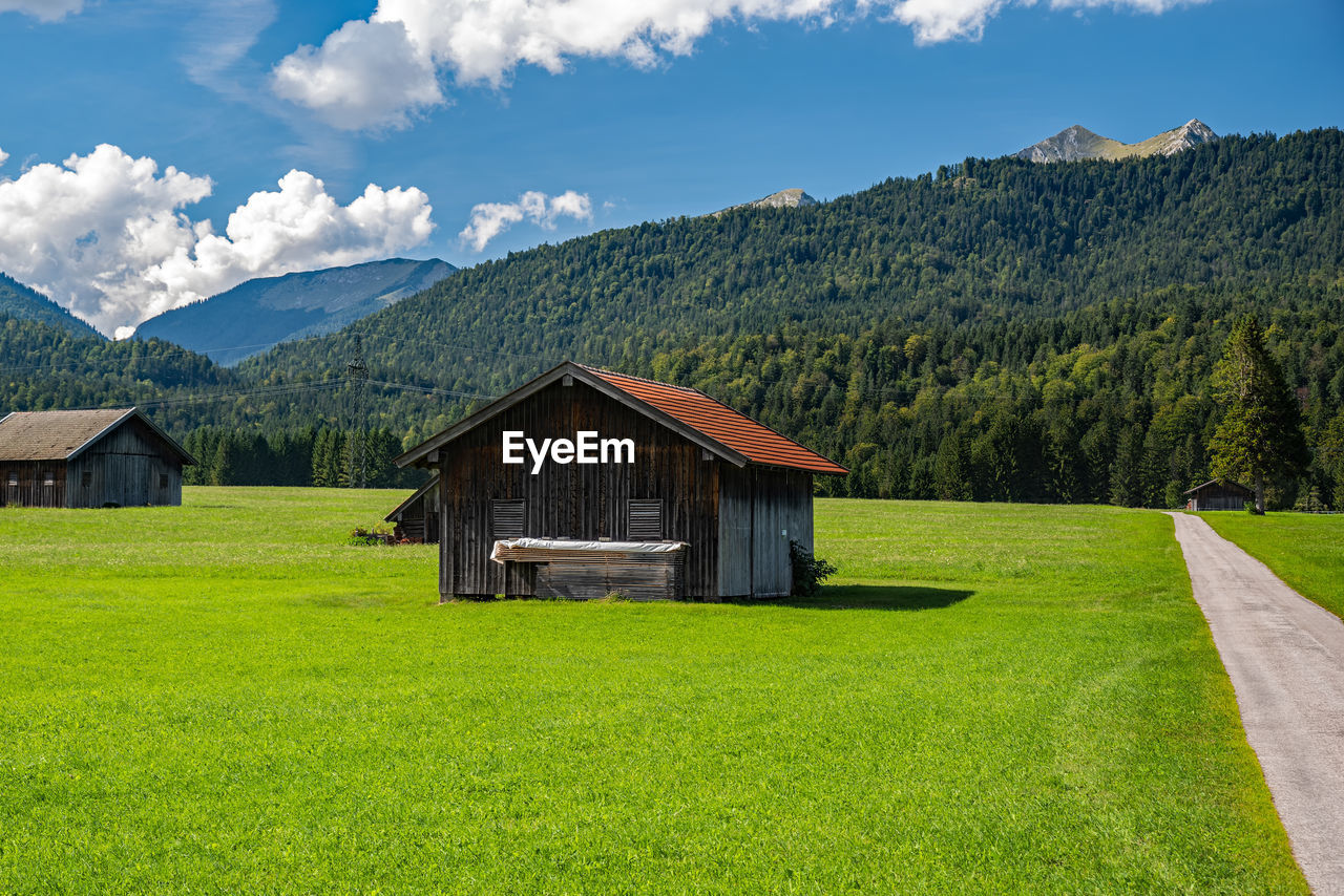 house on field by mountains against sky