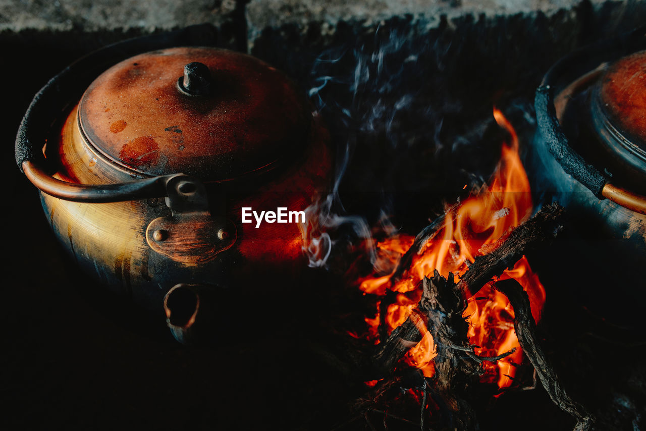 From above of rusty metal kettle placed near flame in campfire in wadi rum