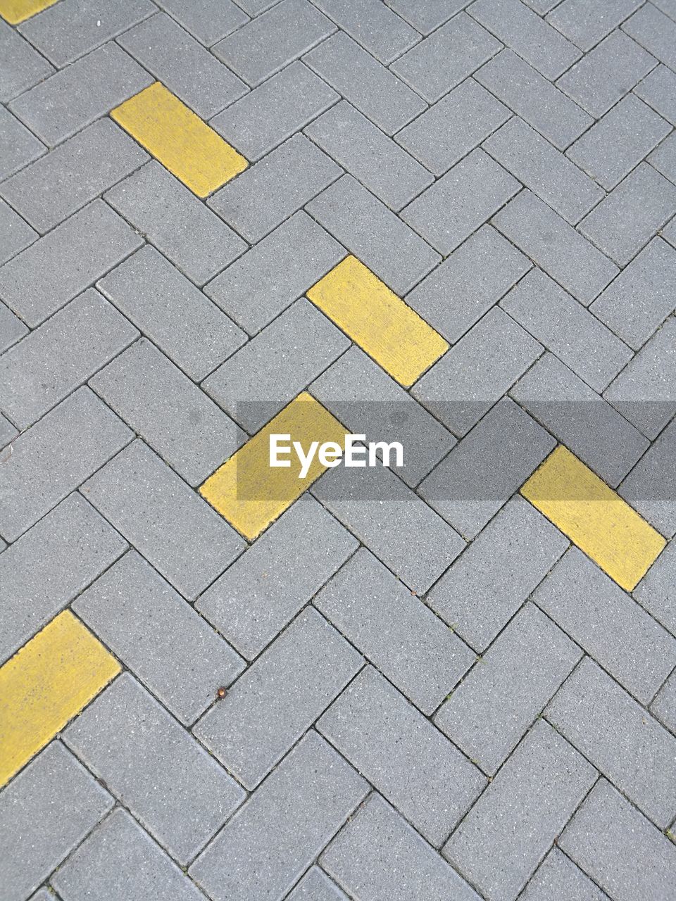HIGH ANGLE VIEW OF YELLOW ARROW SYMBOL ON ROAD
