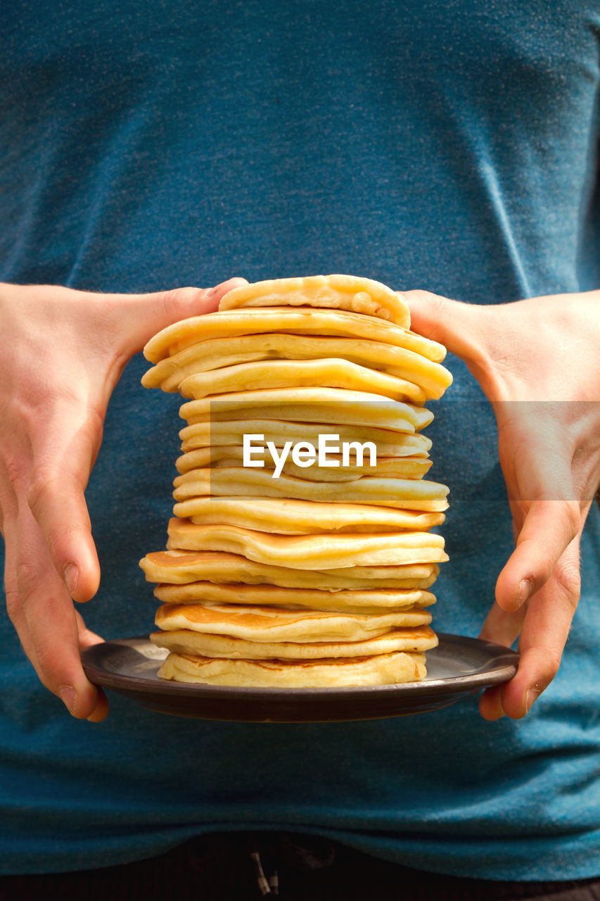 Midsection of man holding pancakes