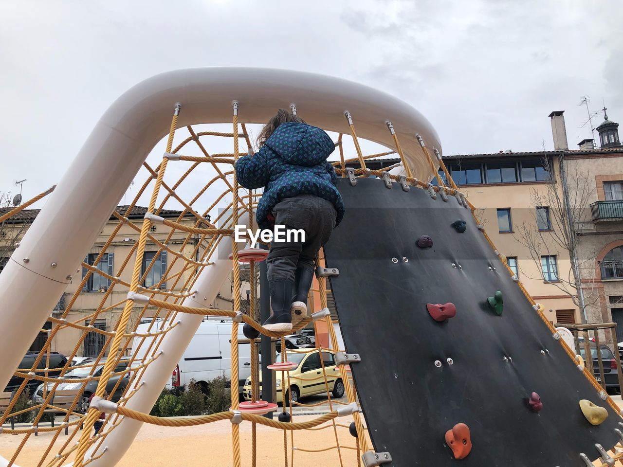 Rear view of girl climbing on play equipment at playground