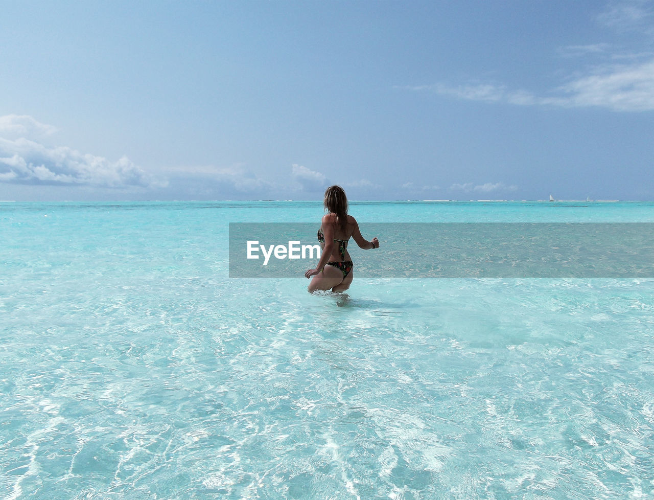 Rear view of blonde woman in shallow water of tropical sea