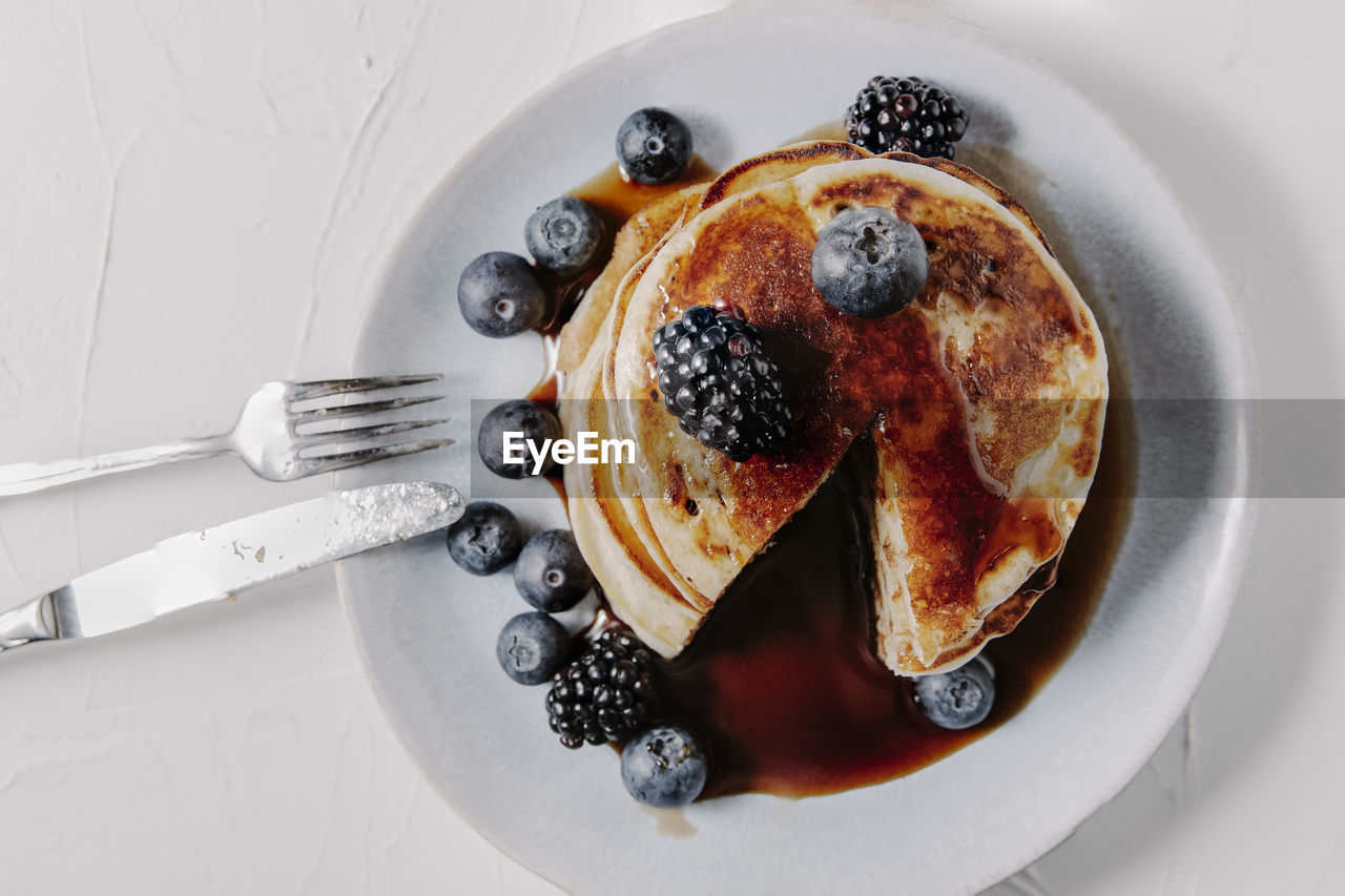 A stack of pancakes with berries and syrup